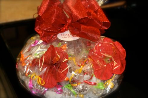 Six Dozen coconut cake balls. EAch one is individually wrapped and tied with bright tropical colors to match the Luau theme. Then placed on a platter with hibiscus to act as a centerpiece.